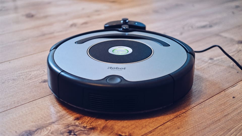 Photograph of a robot vacuum on a hard floor in a small apartment